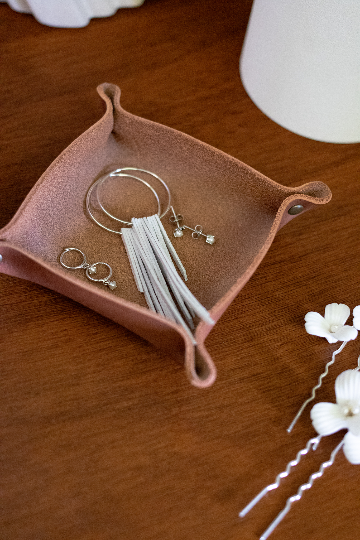 White leather fringe bridal earrings with sterling silver hoops resting in a brown leather jewelry catchall