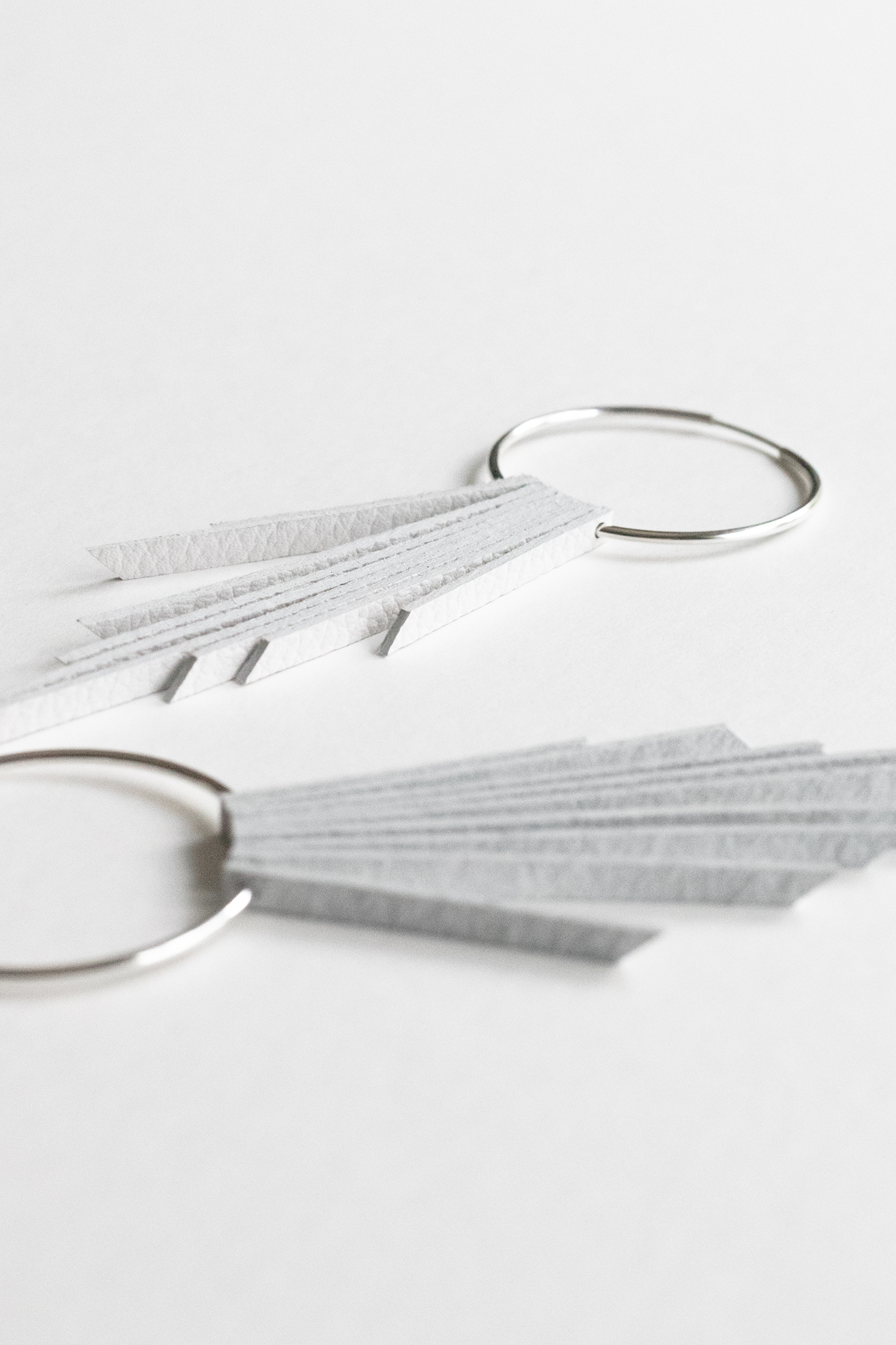 White leather fringe bridal earrings with sterling silver hoops resting on a white backdrop